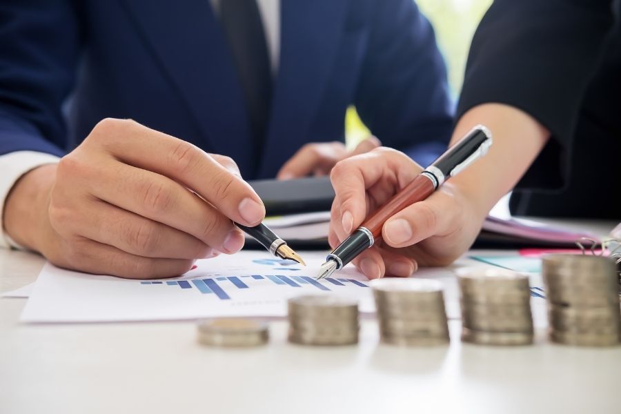 Business professionals analyzing global economic data with charts and coin stacks for 2025 outlook