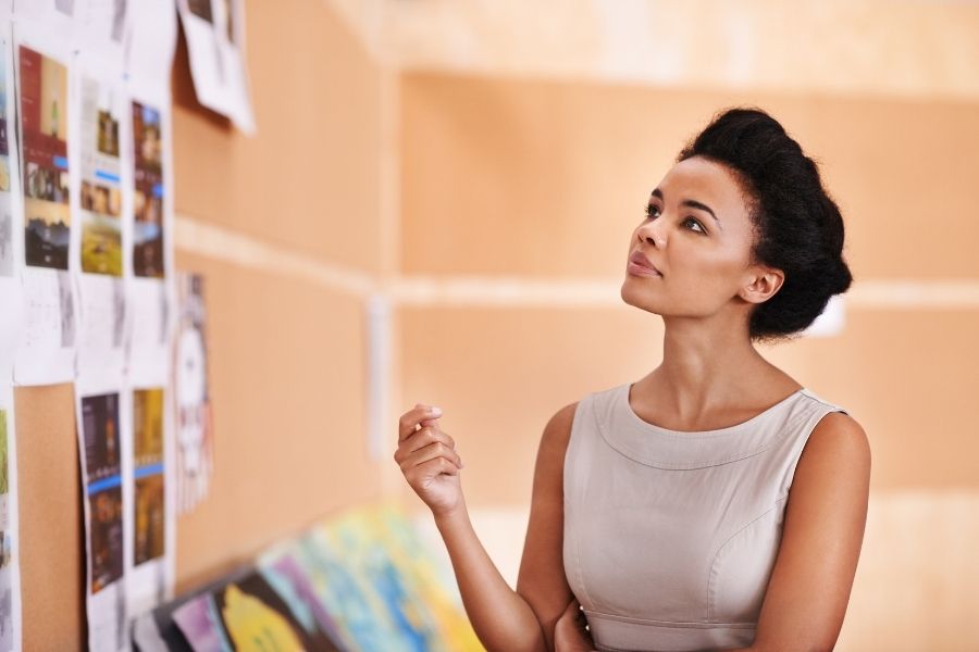 Professional woman examining visual communication materials and creative displays on office wall