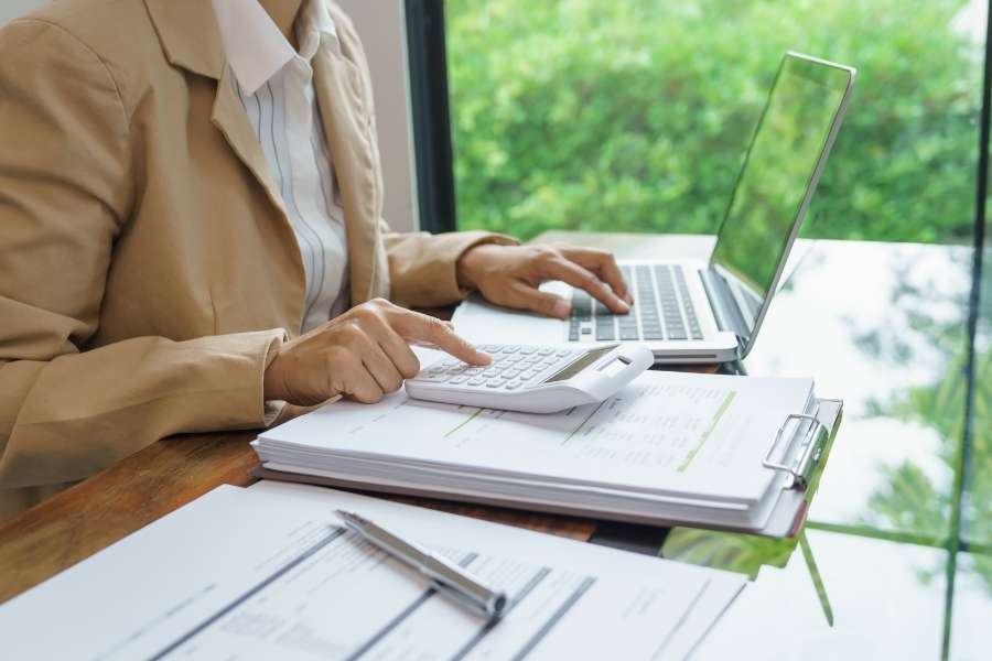 Professional accountant working with calculator and laptop reviewing documents to identify hidden costs first time buyers face