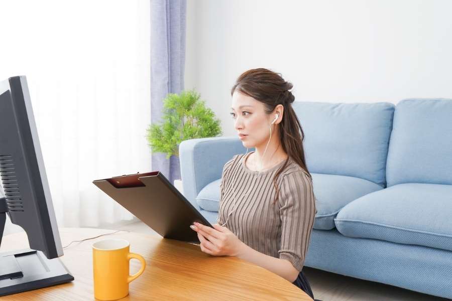 Woman with earphones working on tablet developing remote work skills in modern living room